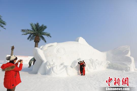 游客在巨型雪雕“鯉魚隧道”前拍照留念。　年磊 攝